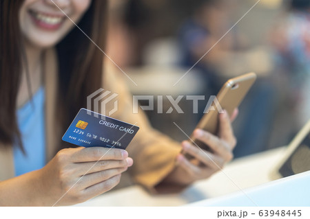 Closeup Asian woman using credit card with mobile for online shopping in department store over the clothes shop store background, technology money wallet and online payment concept, credit card mockup Closeup Asian woman using credit card with mobile for online shopping in department store over the clothes shop store background, technology money wallet and online payment concept, credit card mockup 63948445