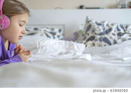 Girl in pink headphones with tablet device 63948560