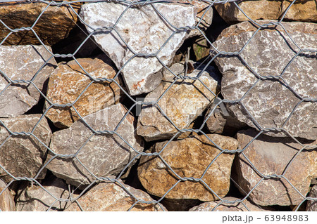 Stones in a metal grid as an abstract background Stones in a metal grid as an abstract background 63948983