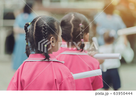 Back view of little girls use paper rolls instead of long cheerleader Baton Sticks for school parade marching practice. Back view of little girls use paper rolls instead of long cheerleader Baton Sticks for school parade marching practice. 63950444