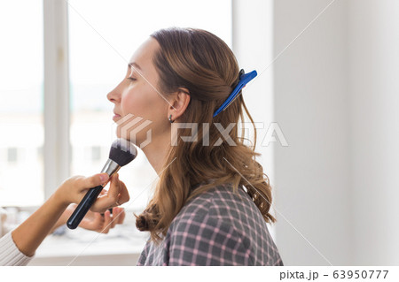 Beauty and cosmetics concept - Makeup artist doing professional make up of young woman 63950777