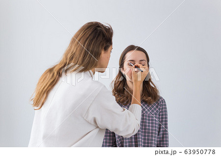 Beauty and cosmetics concept - Makeup artist doing professional make up of young woman 63950778