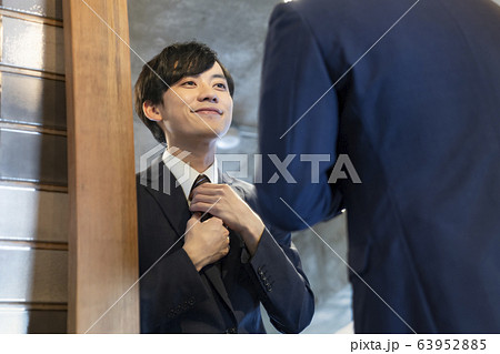 鏡を見ながらネクタイ を整える若い男性 63952885
