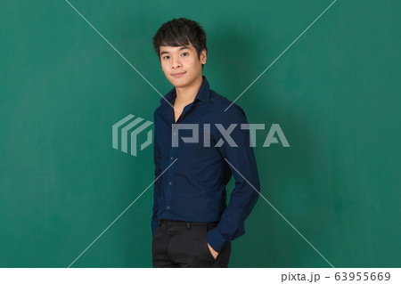 Young Asian man standing at green wall. 63955669