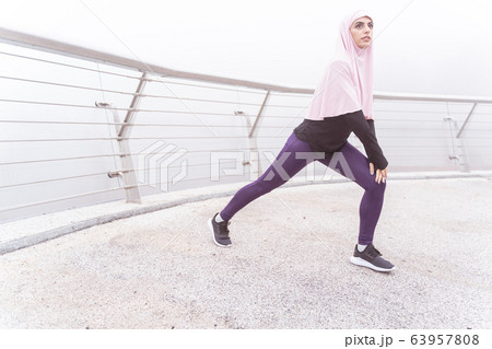 Calm athlete near the banister doing sports exercises stock photo 63957808