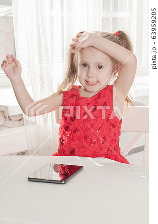 little girl in a red dress sits at a table and 63959205