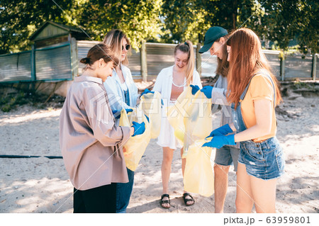 Group of activists friends collecting plastic waste on the beach. Environmental conservation. 63959801