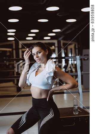 Smiling fit girl holding towel and taking rest in gym. 63959808