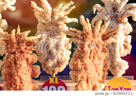 Large fried Japanese squid fried on skewers for sale in street food in Thailand. Large fried Japanese squid fried on skewers for sale in street food in Thailand. 63964221