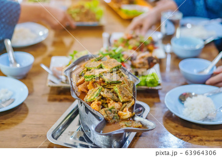 Group of female friends enjoy eating with acacia pennata omelette sour soup in fish shape hot pot in the restaurant. Selective focus. Group of female friends enjoy eating with acacia pennata omelette sour soup in fish shape hot pot in the restaurant. Selective focus. 63964306