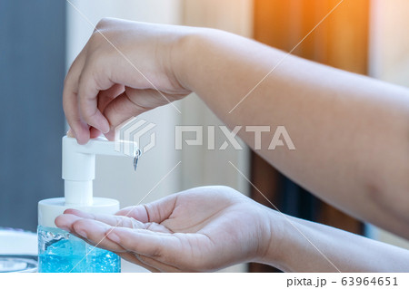 Young woman uses her hand to press hand sanitizer bottle to clean her hand. Hand sanitizer alcohol gel rub clean hands hygiene prevention of coronavirus virus outbreak. 63964651