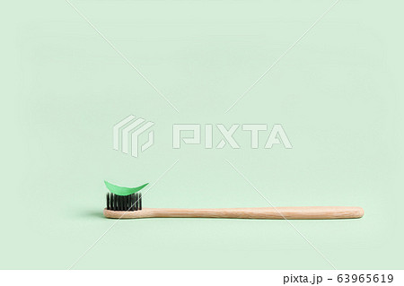 Minimalistic background with one wooden toothbrush and a mint paper leaf Minimalistic background with one wooden toothbrush and a mint paper leaf 63965619
