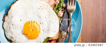 Breakfast or lunch with fried egg, bread toast, green asparagus, tomatoes and bacon Breakfast or lunch with fried egg, bread toast, green asparagus, tomatoes and bacon 63965987