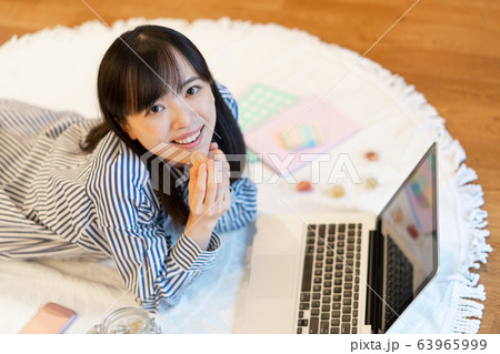 リビングで横になりながら、お菓子を食べる若い女性 63965999