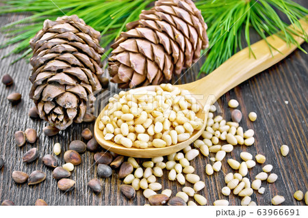 Cedar nuts peeled in spoon on wooden board 63966691