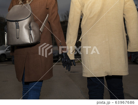 Couple wearing black nitrile gloves walking on the street and holding their hands Couple wearing black nitrile gloves walking on the street and holding their hands 63967686