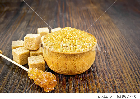 Sugar brown in bowl on dark wooden board 63967740