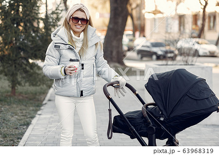 Stylish woman walking in a city with carriage Stylish woman walking in a city with carriage 63968319