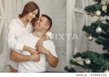 Elegant couple sitting on a bed near christmas tree 63969158