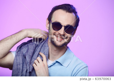 Studio shot of handsome man wearing sunglasses over pink background. Studio shot of handsome man wearing sunglasses over pink background. 63970063