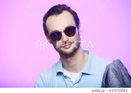 Studio shot of handsome man wearing sunglasses over pink background. Studio shot of handsome man wearing sunglasses over pink background. 63970065