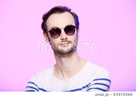 Studio shot of handsome man wearing sunglasses over pink background. 63970066