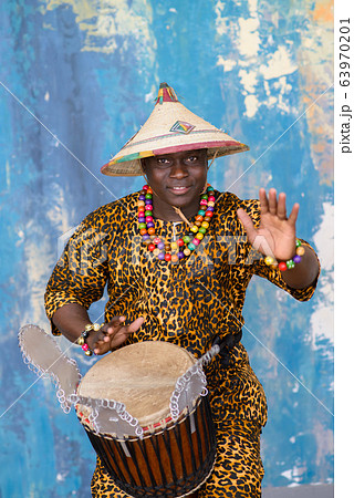 Handsome african drummer weared in traditional costume playing on djembe drum 63970201