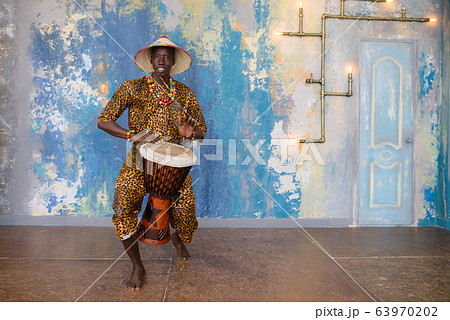 African man in traditional clothes playing djembe drum 63970202