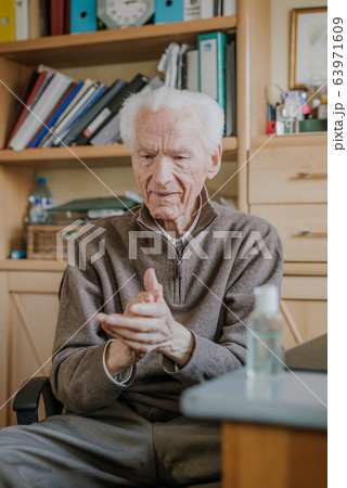 Senior disinfects hands with antibacterial gel 63971609