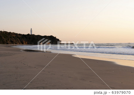 朝焼けの灯台の見える砂浜の風景 63979070