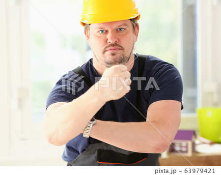 Smiling funny worker in yellow helmet posing 63979421