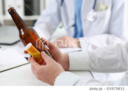 Alcoholic hold in hand empty bottle at doctor reception Alcoholic hold in hand empty bottle at doctor reception 63979831