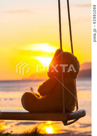 Teddy Bear sitting on a swing at sunrise. Teddy Bear sitting on a swing at sunrise. 63981088