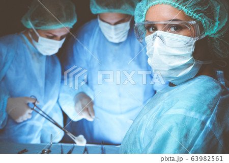 Group of surgeons wearing safety masks performing operation. Medicine concept 63982561