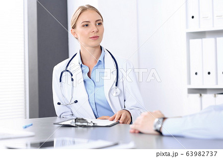 Doctor and patient in clinic. Beautiful blonde physician consulting business man about his health. Medicine concept 63982737