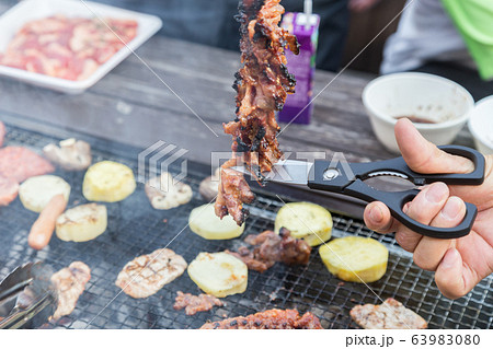 バーベキューで肉をハサミで切る手元 バーベキューで肉をハサミで切る手元 63983080