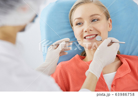 Smiling caucasian woman is being examined by dentist at dental clinic. Healthy teeth and medicine, stomatology concept Smiling caucasian woman is being examined by dentist at dental clinic. Healthy teeth and medicine, stomatology concept 63986758