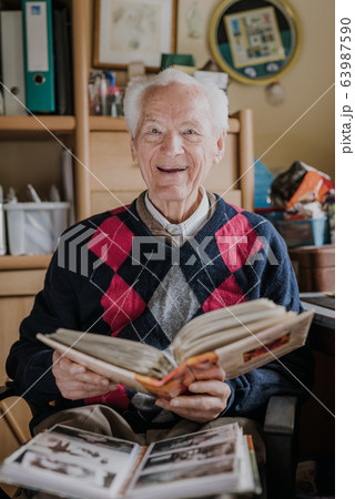 Old man looking at old albums with family photos Old man looking at old albums with family photos 63987590