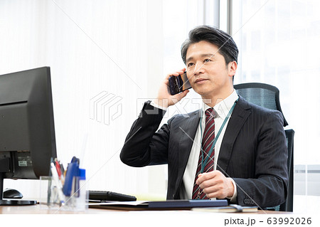 オフィスでスマホで話をする部長 オフィスでスマホで話をする部長 63992026