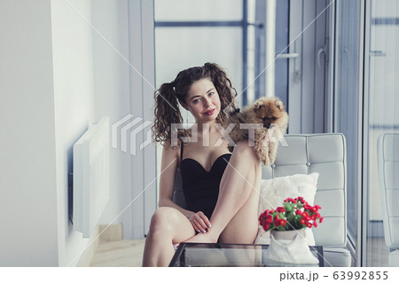 woman sitting with a Pomeranian Spitz dog 63992855