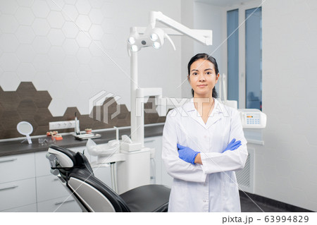 Young confident blunette female dentist in whitecoat and gloves 63994829