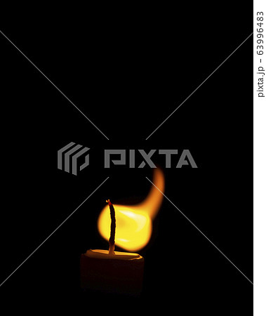 Vivid flame of a wax candle curiously curved and froze in black darkness Vivid flame of a wax candle curiously curved and froze in black darkness 63996483