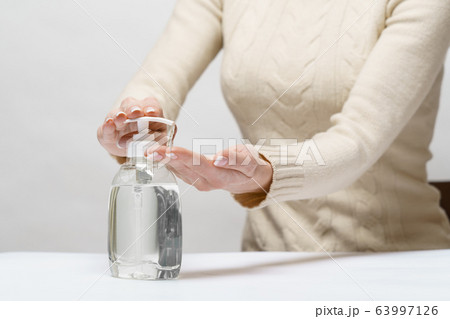 Female hands using hand sanitizer gel or liquid soap dispenser over light grey background 63997126