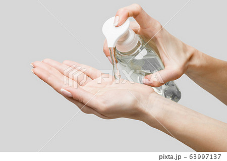 Female hands using hand sanitizer gel or liquid soap dispenser over light grey background 63997137