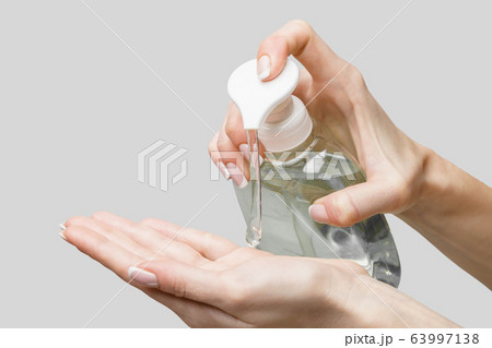 Female hands using hand sanitizer gel or liquid soap dispenser over light grey background 63997138