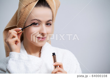 Pretty girl doing cosmetic procedures at home in front of mirror Pretty girl doing cosmetic procedures at home in front of mirror 64000108