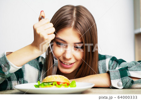 Nice woman wants to eat hamburger harmful 64000333