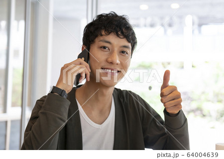 スマホで通話しながら「いいね!」をする男性 スマホで通話しながら「いいね!」をする男性 64004639