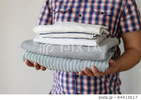 Stack of clean laundered clothes in man hands Stack of clean laundered clothes in man hands 64013617