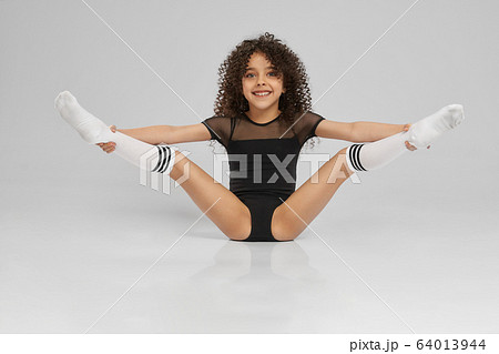 Young female gymnast demonstrating flexibility. 64013944